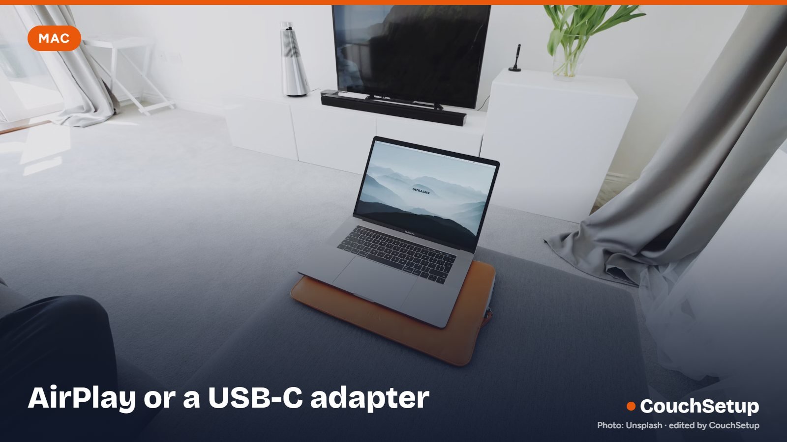 A MacBook on a desk near a TV