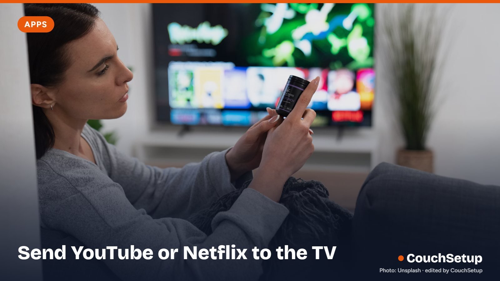 Someone on a couch holding a phone in front of a TV