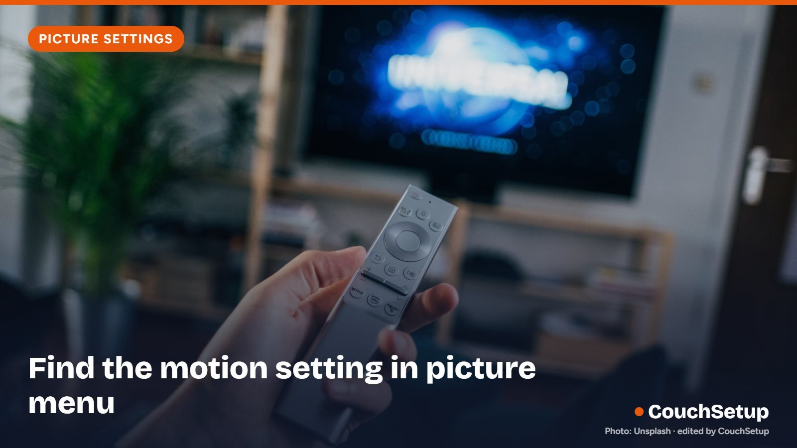 A hand pointing a TV remote at the screen