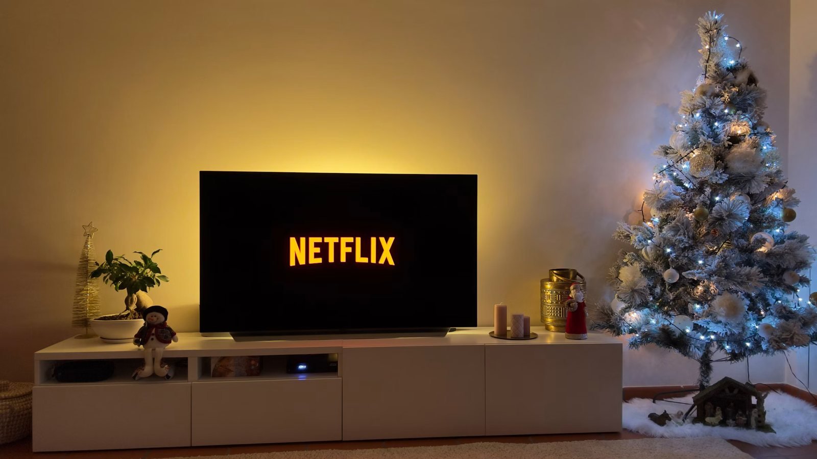 A TV with a soft glow behind it next to a Christmas tree