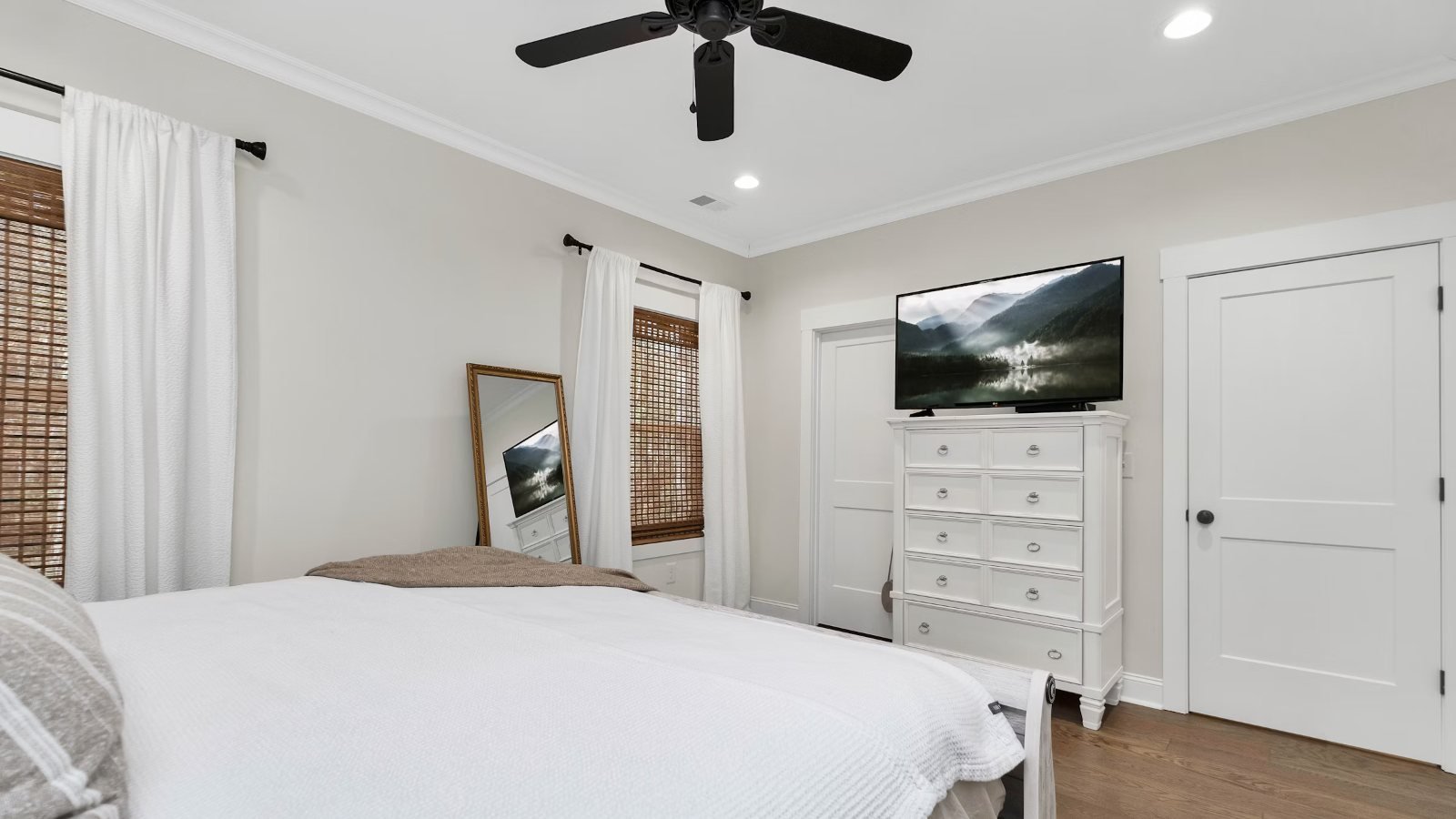 A TV on a dresser facing the bed in a bedroom